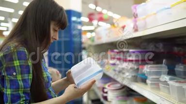 一个年轻的女人选择并在超市买一个塑料容器作为食物。